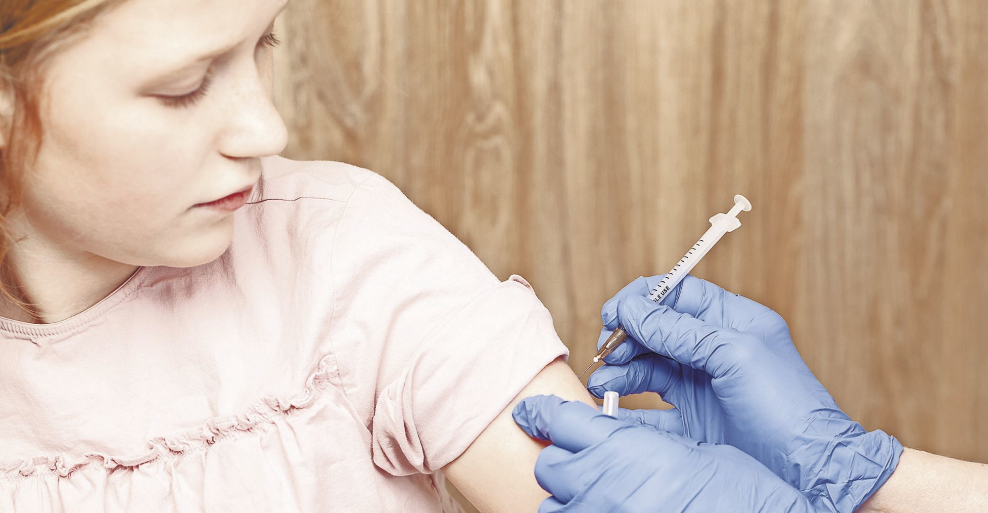 Close-up shot of pediatrician giving an intramuscular injection of a vaccine to a preteen girl's arm